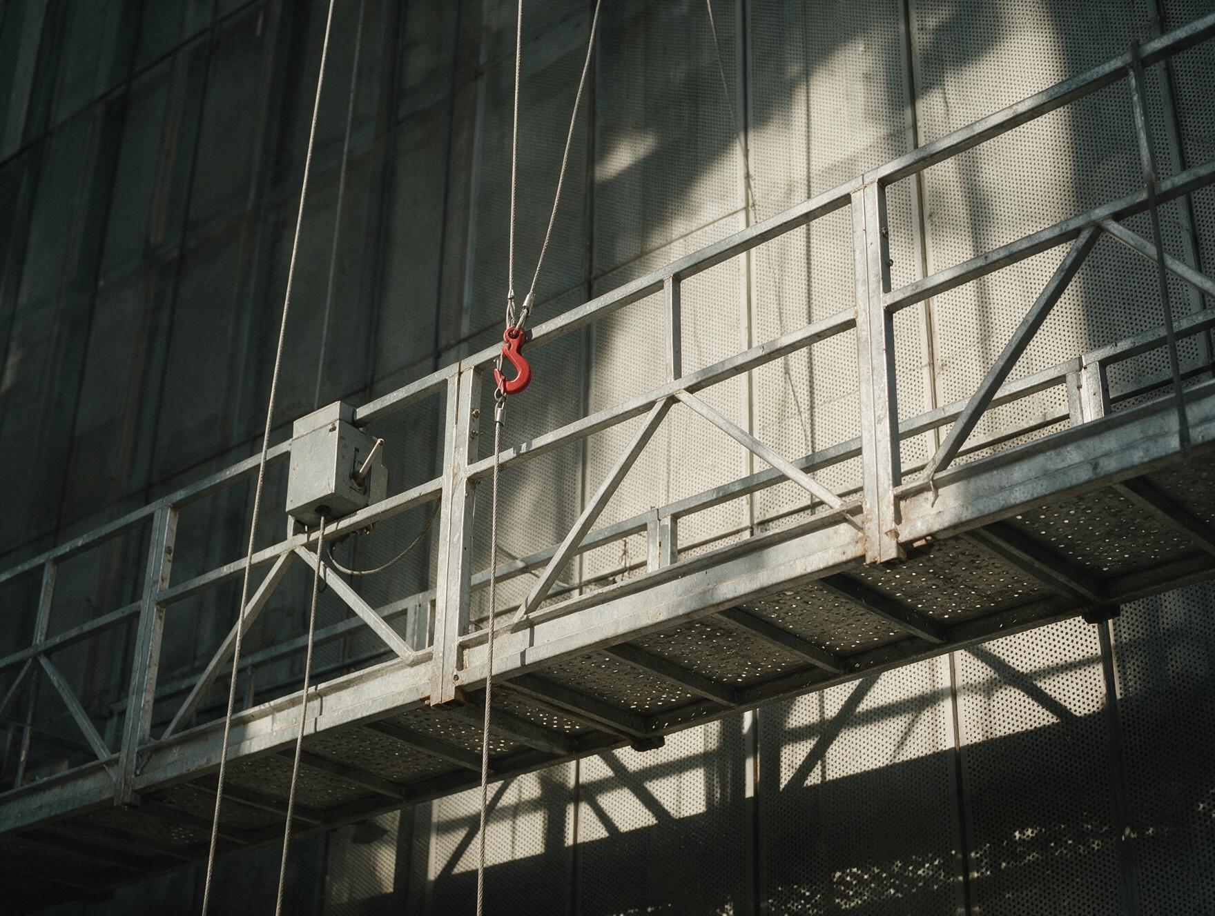 Échafaudage volant suspendu contre une façade industrielle