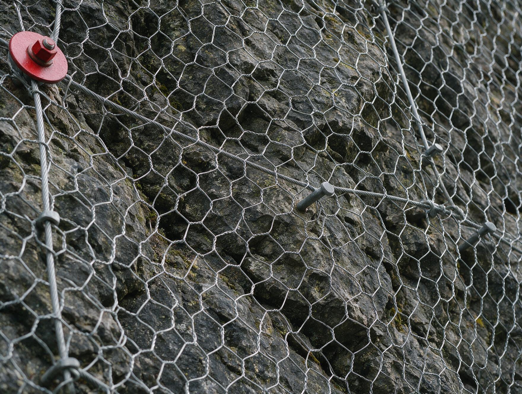 Filet de protection pare-blocs ancré sur une paroi rocheuse